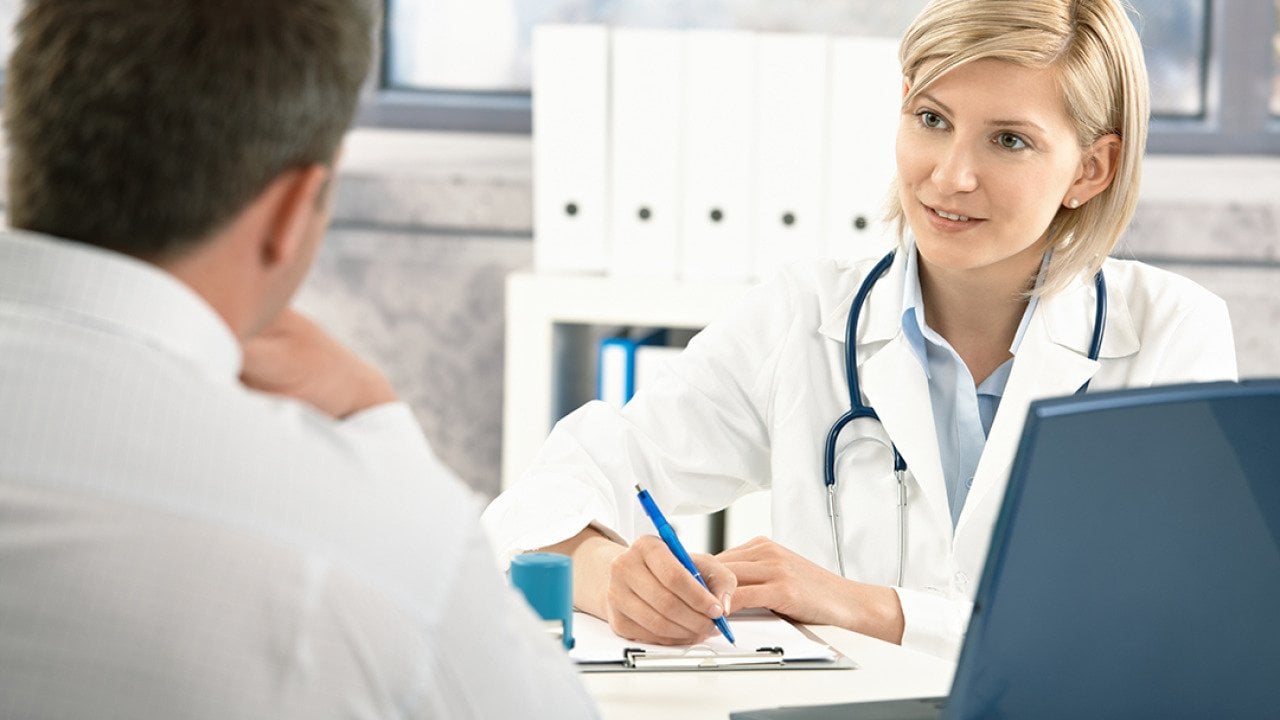 A doctor takes notes while consulting with her patient.