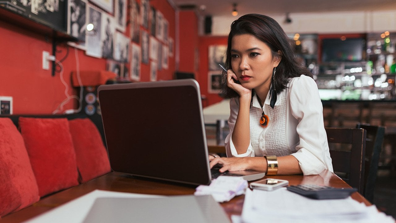A female bar owner using her laptop to pay business expenses online.