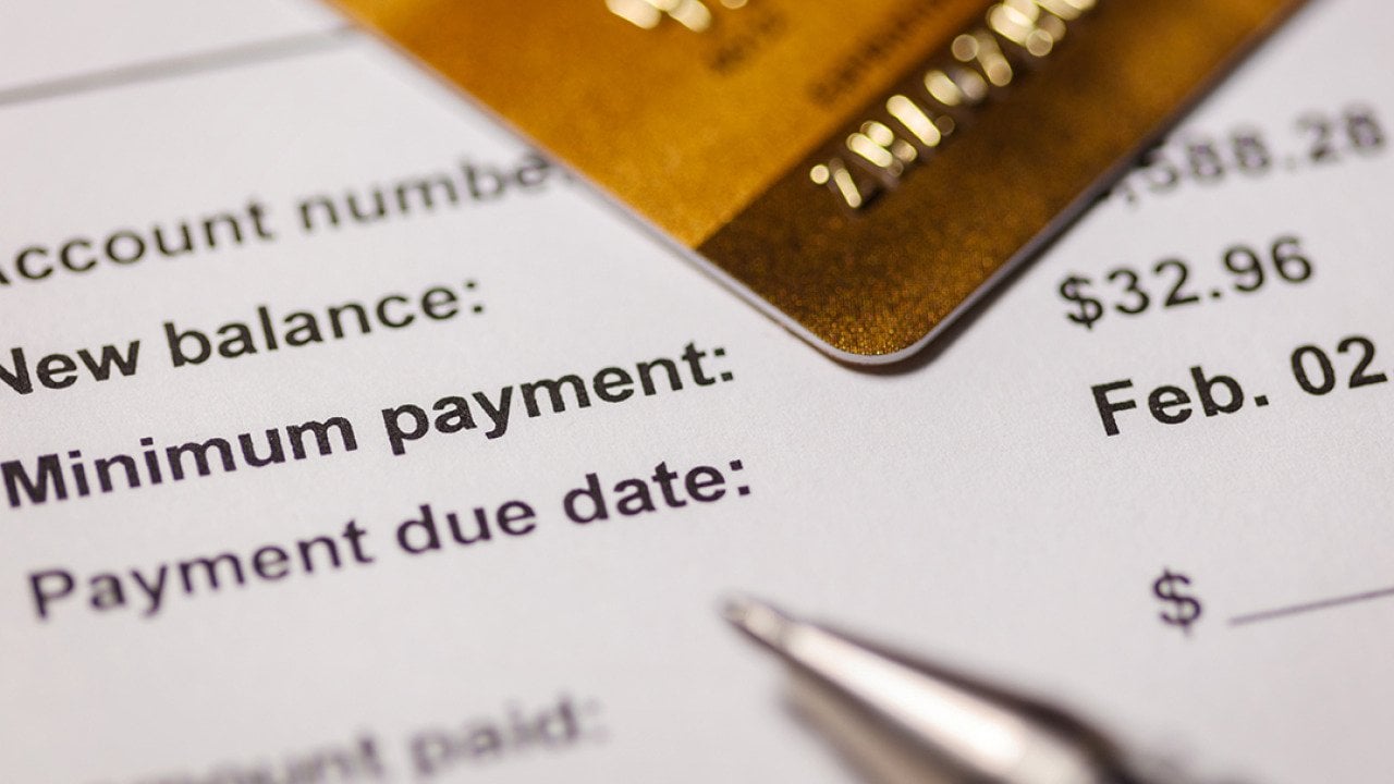 Credit card on top of a bill statement closed up on the minimum amount and due date.
