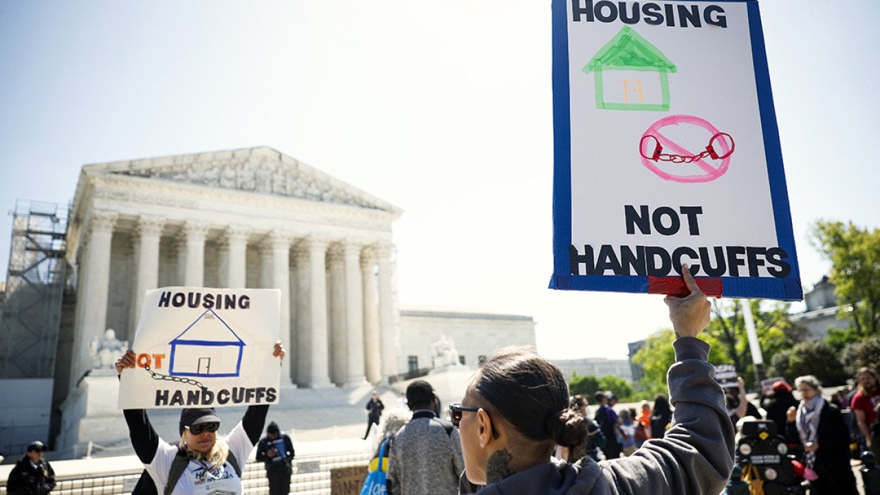 Homeless rights activists hold up signs saying 
