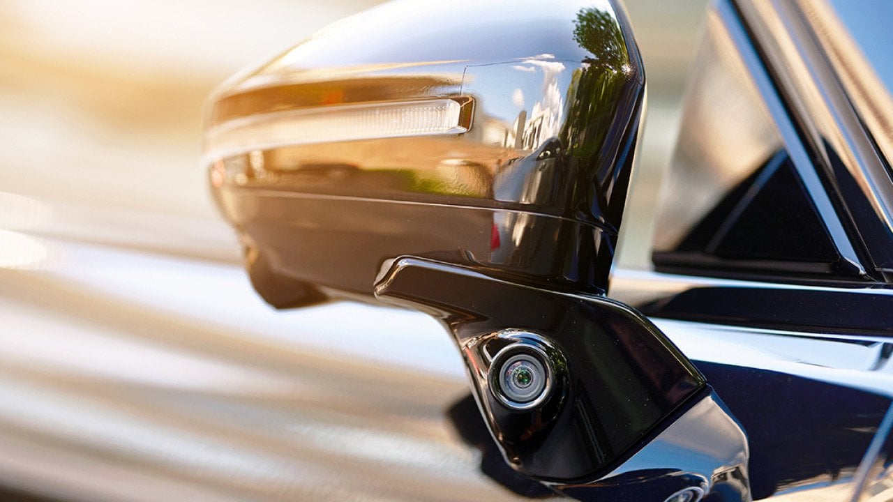 Side area of a car showing the rear mirror for blind spot monitoring.