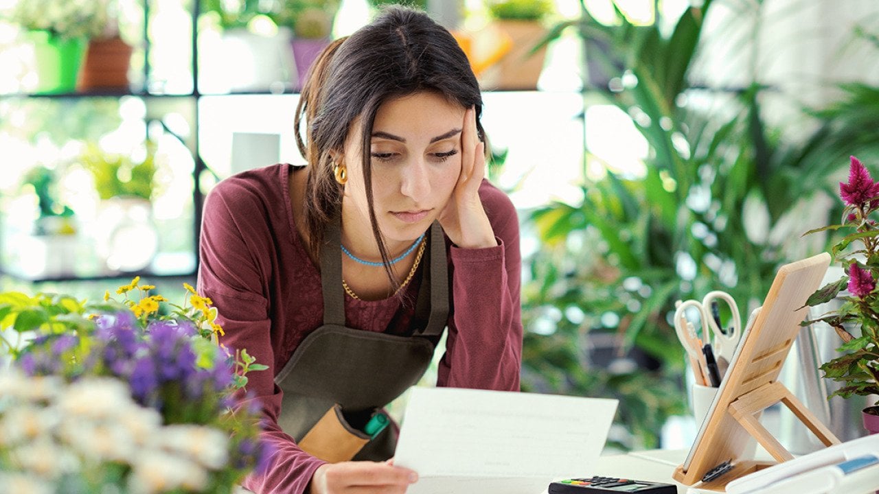 A small plants business owner worried looking at a bill.