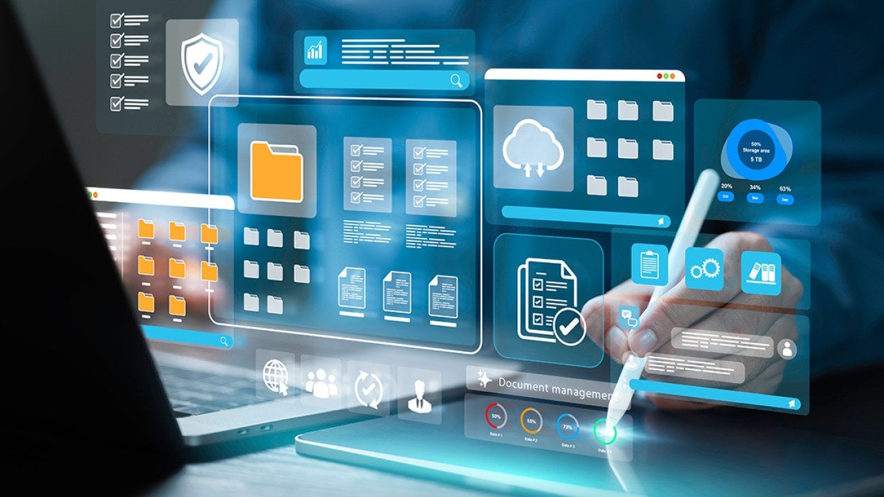 Employee working on a laptop with holographic illustrations of document management software concepts.