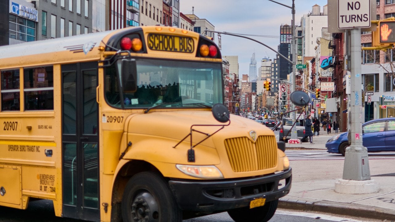 A yellow school bus passing a street in New York City.