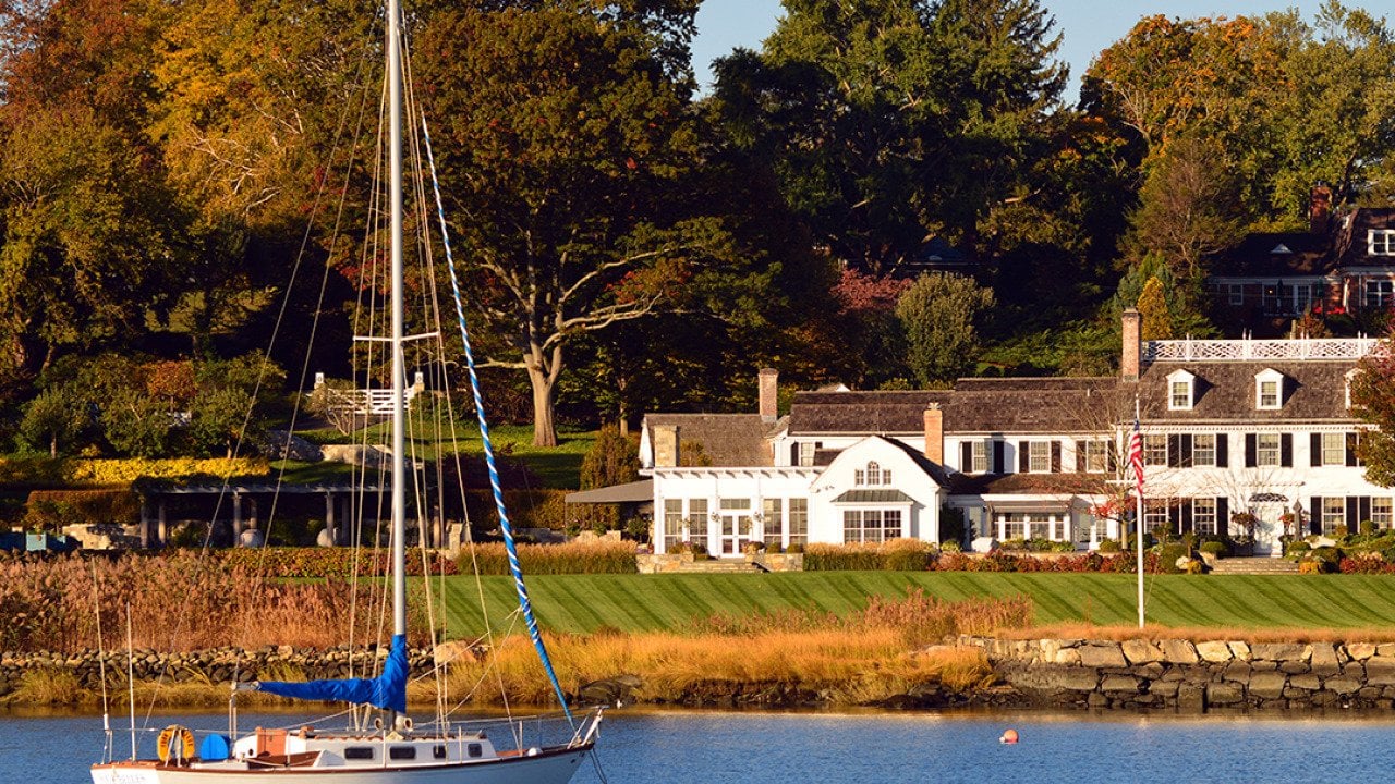 A sailboat moored off-shore near a luxury waterfront home in Greenwich, Connecticut.