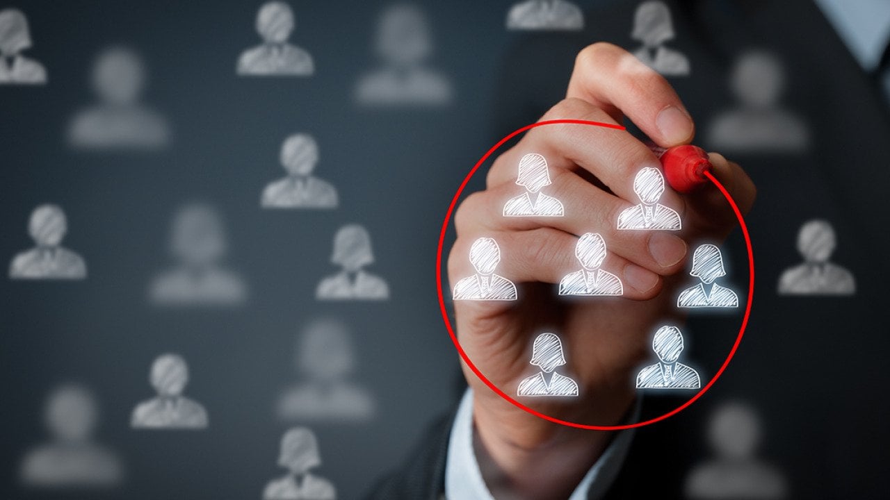 A hand encircling a group of business people graphic figures with a red marker.