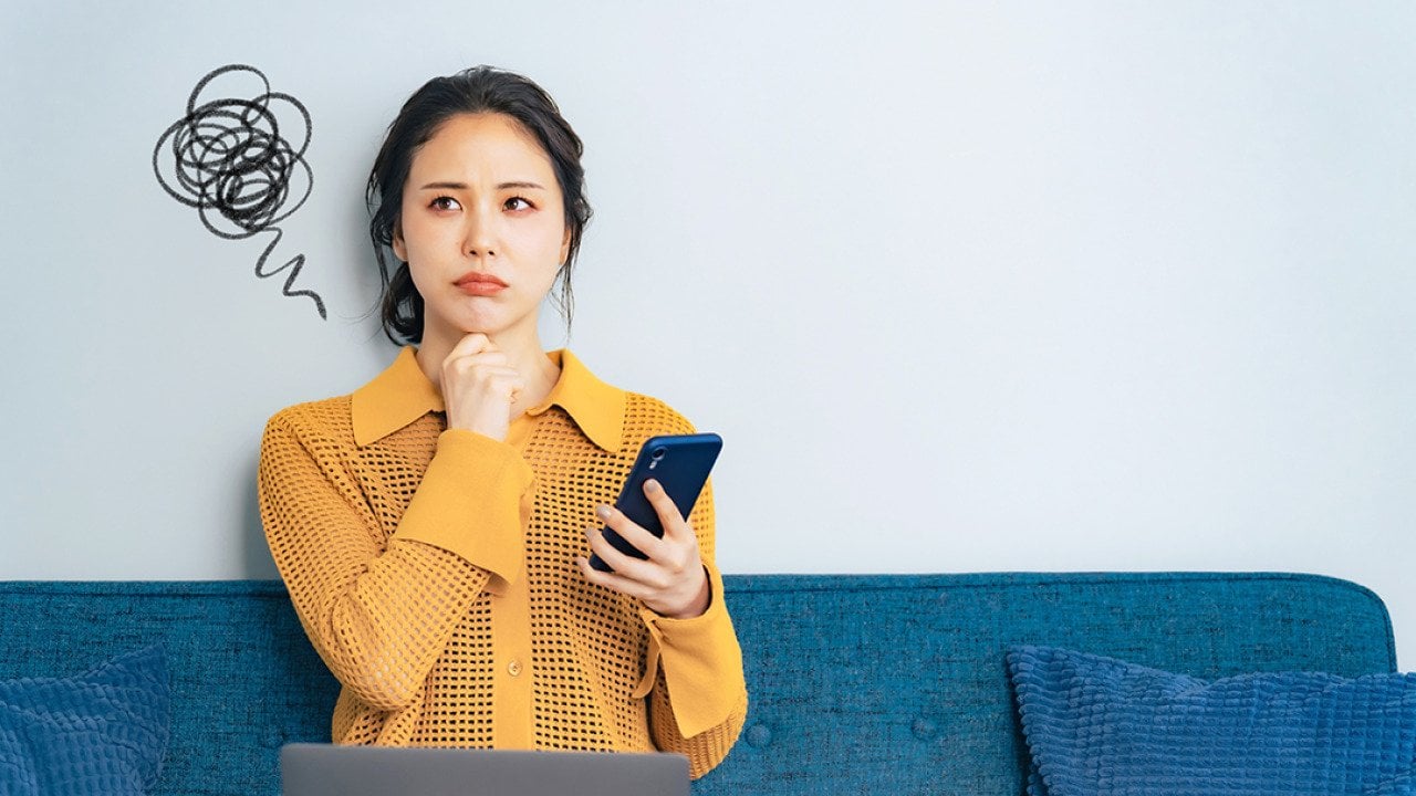 A young woman trying to think of an idea while holding her phone.