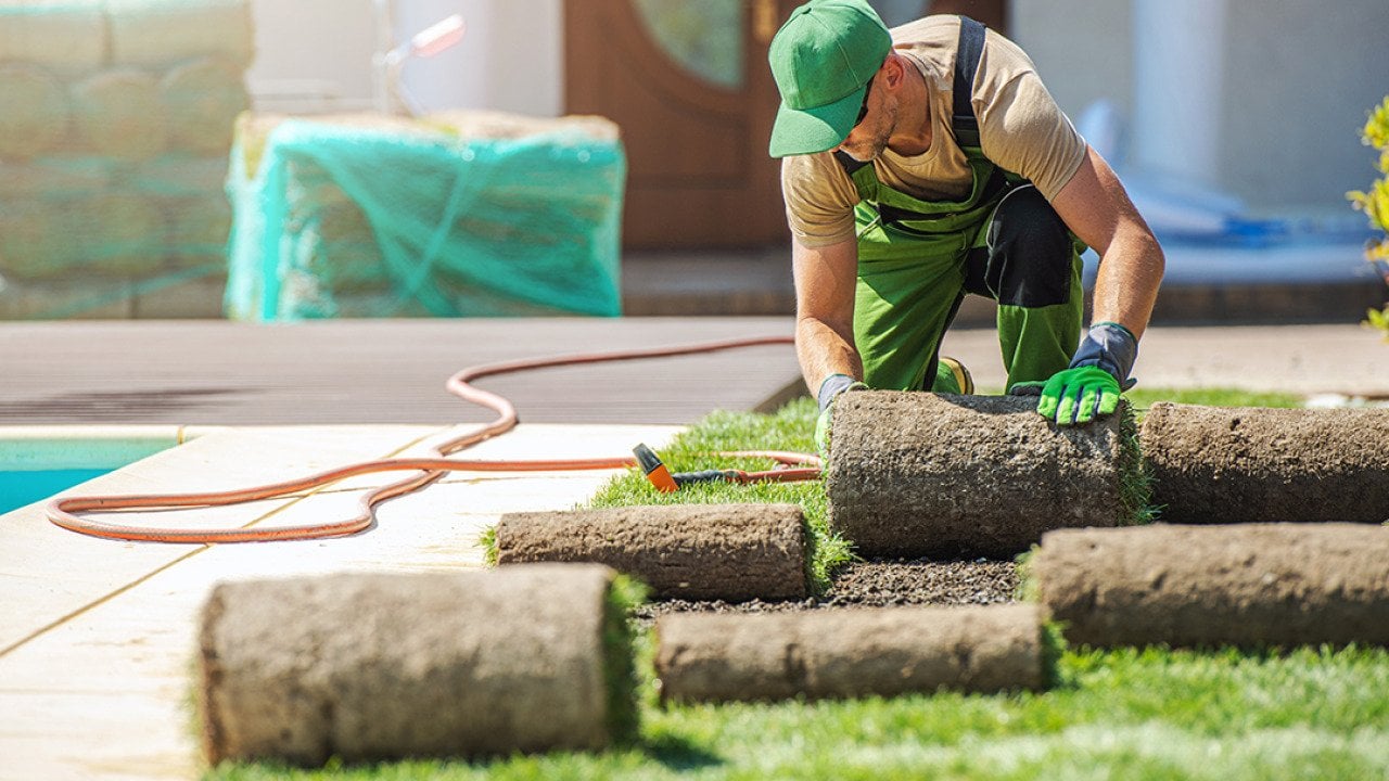A lawn care professional installing new grass at a home.