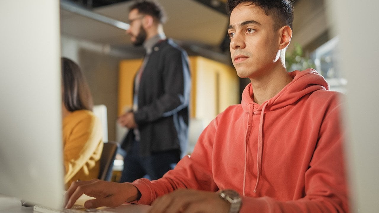 A male student using a desktop computer for application tasks.