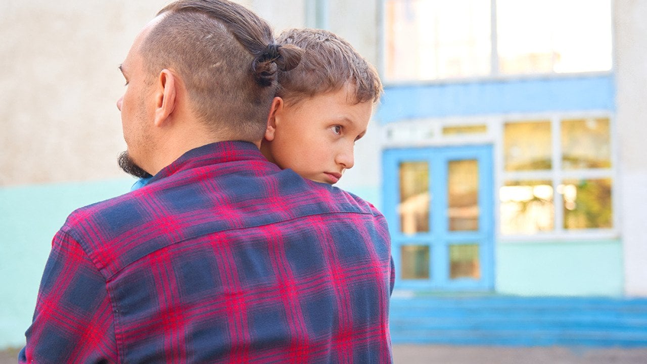 A father hugs his young son before leaving for school.