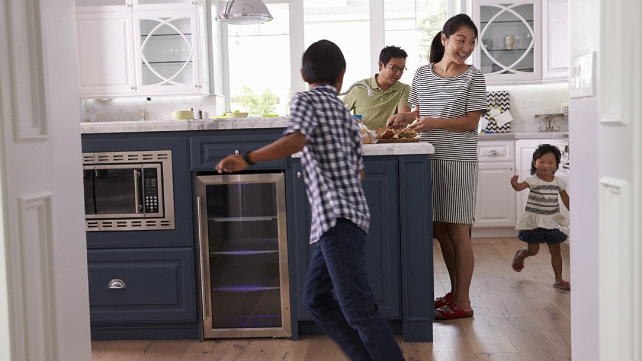 Parents prepare food as their children play around the kitchen.