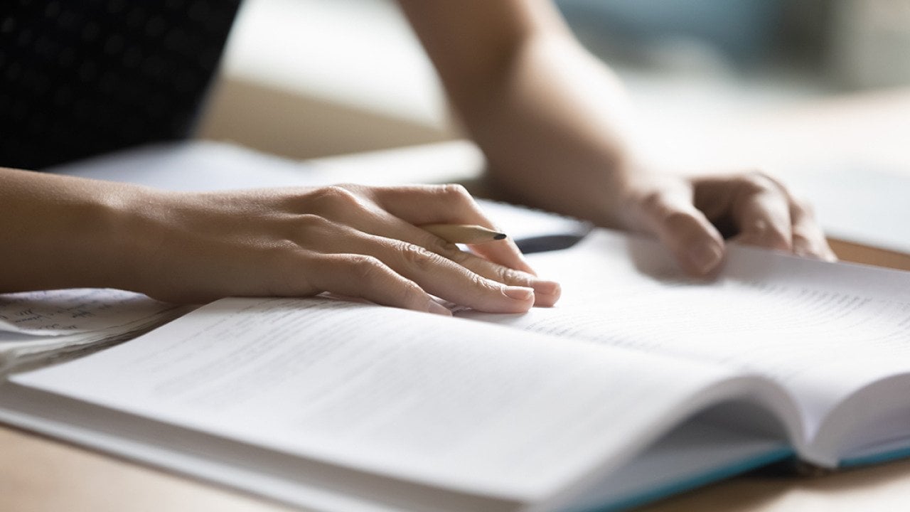 Student reading a book preparing for a college test.