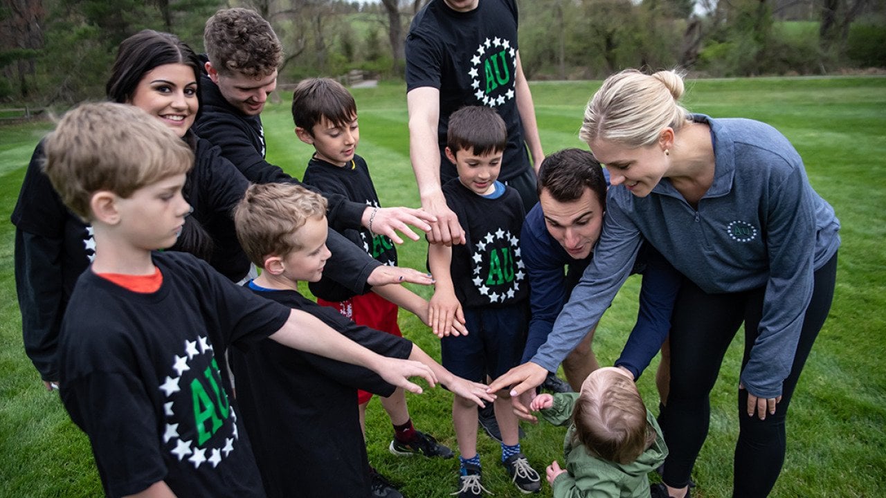 A group of young kinds with their parents form a circle to join hands before a game.