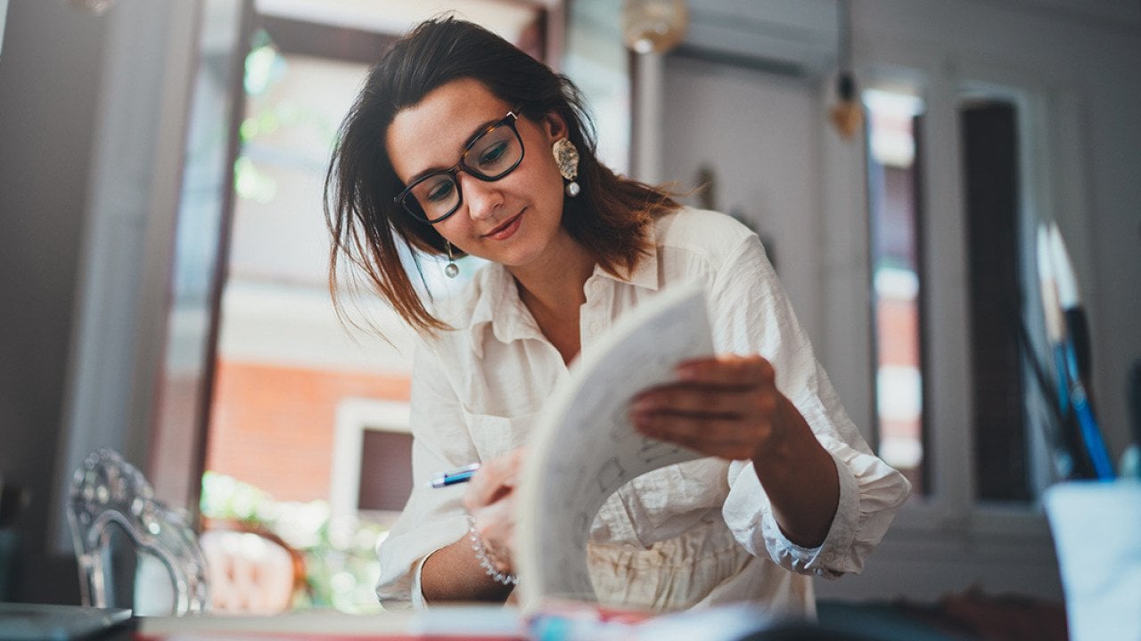 A freelance female designer browsing her design book in a studio.