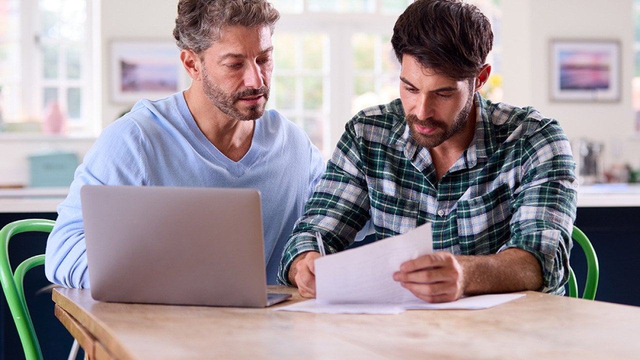 A gay couple at home checking finance documents.