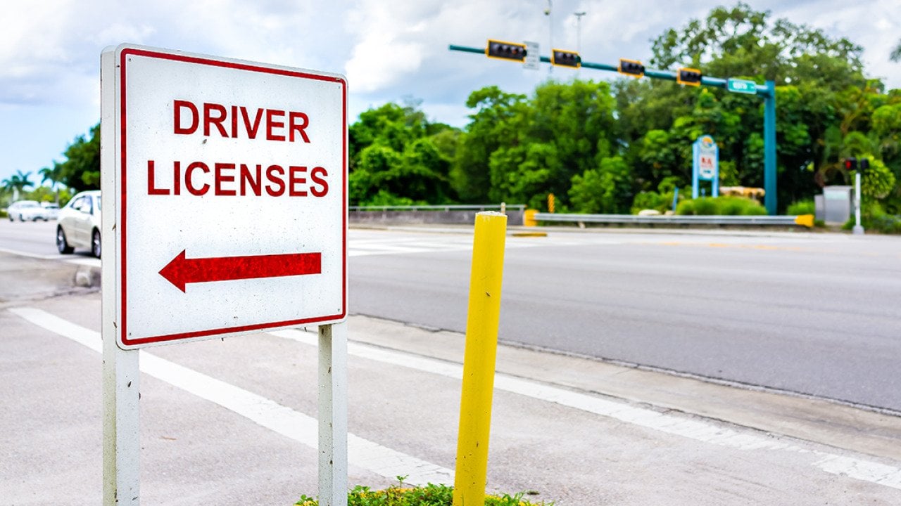 A roadside sign showing direction to a driver's license office.