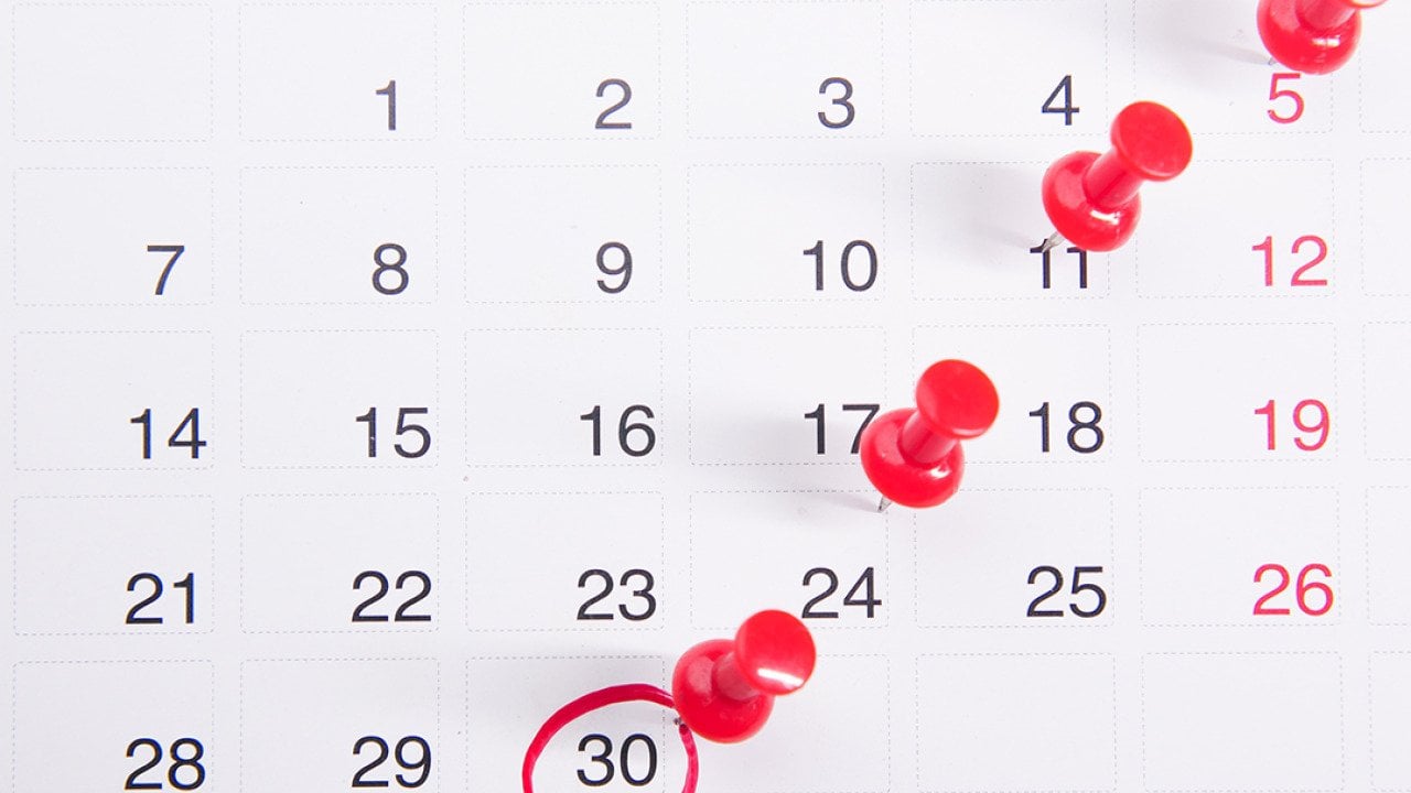 Pushpins on a calendar with an encircled date.