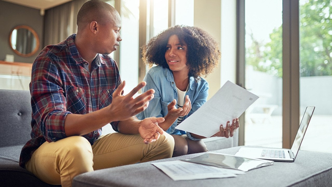 A young couple discussing finances while holding paperwork.