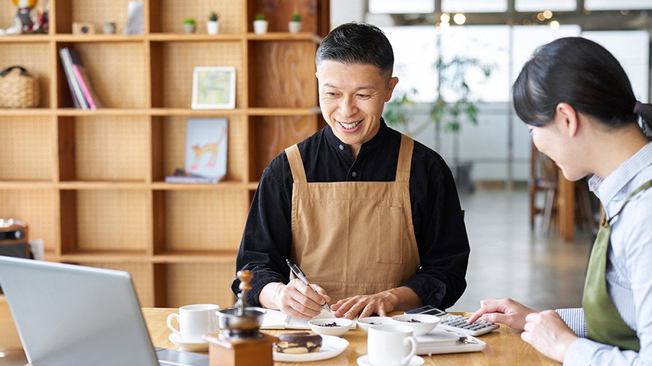 A cafe small business owner calculating costs of products.