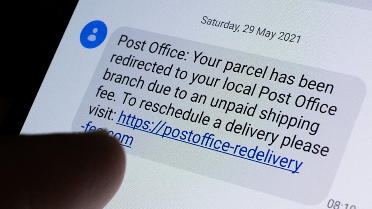 Phone displaying a USPS scam text message with a link.