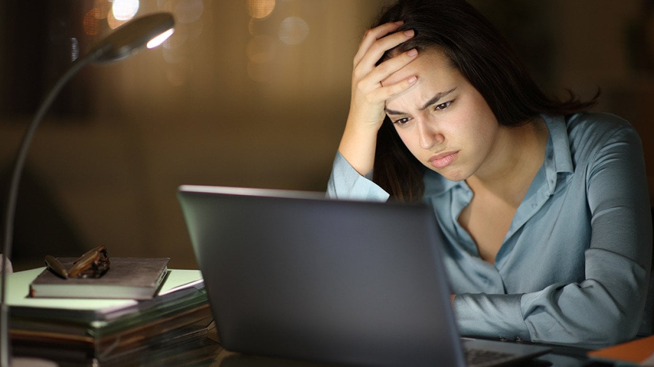 A young female professional frustratingly looks at her laptop at work.