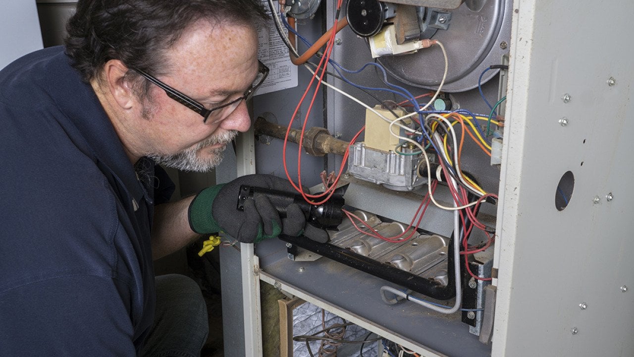 A technician inspects a gas furnace before its cleaning.