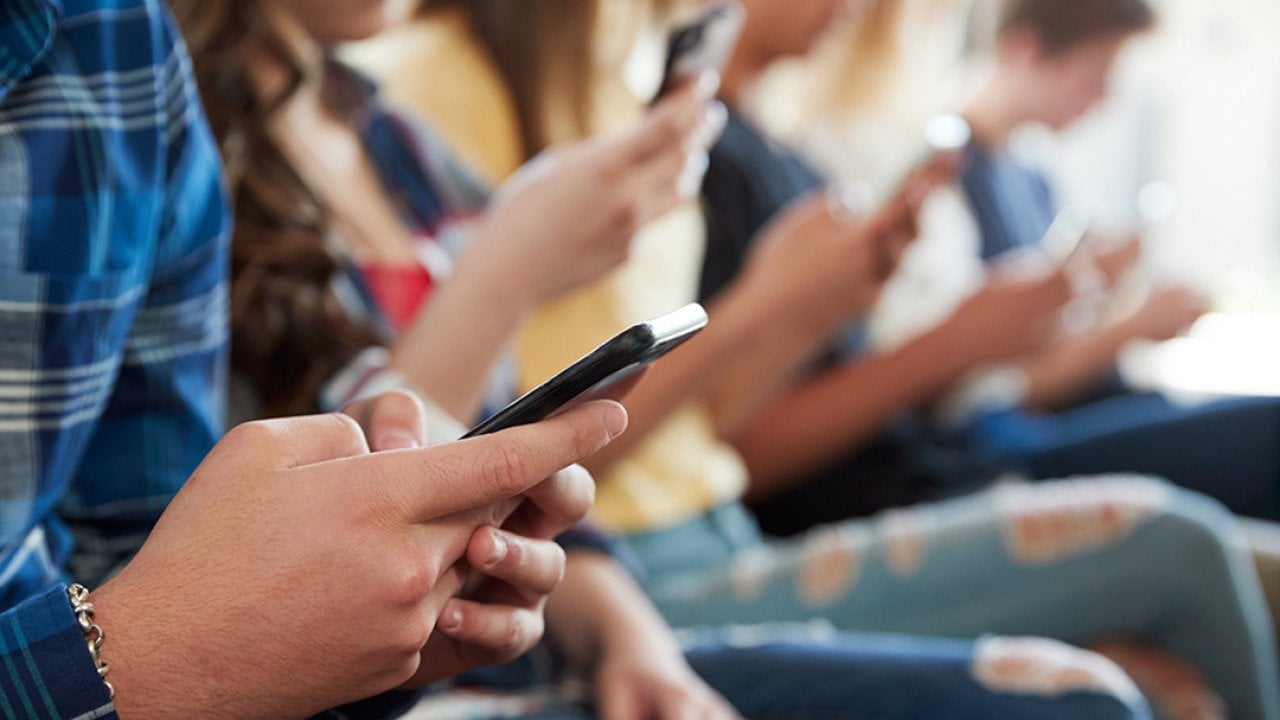 A row of high school students using mobile phones.