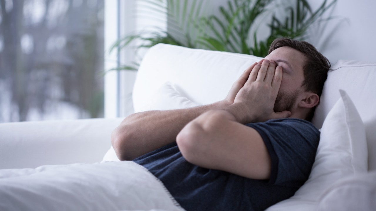A man on bed struggling to sleep.