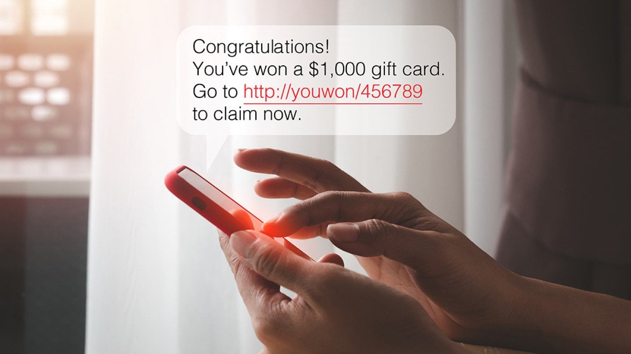 SMS chat bubble displaying a cash prize message over a person typing on a smartphone.
