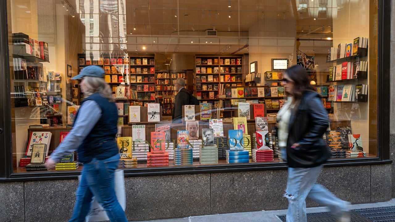 People passing by the glass display of a book store in Manhattan, New York.