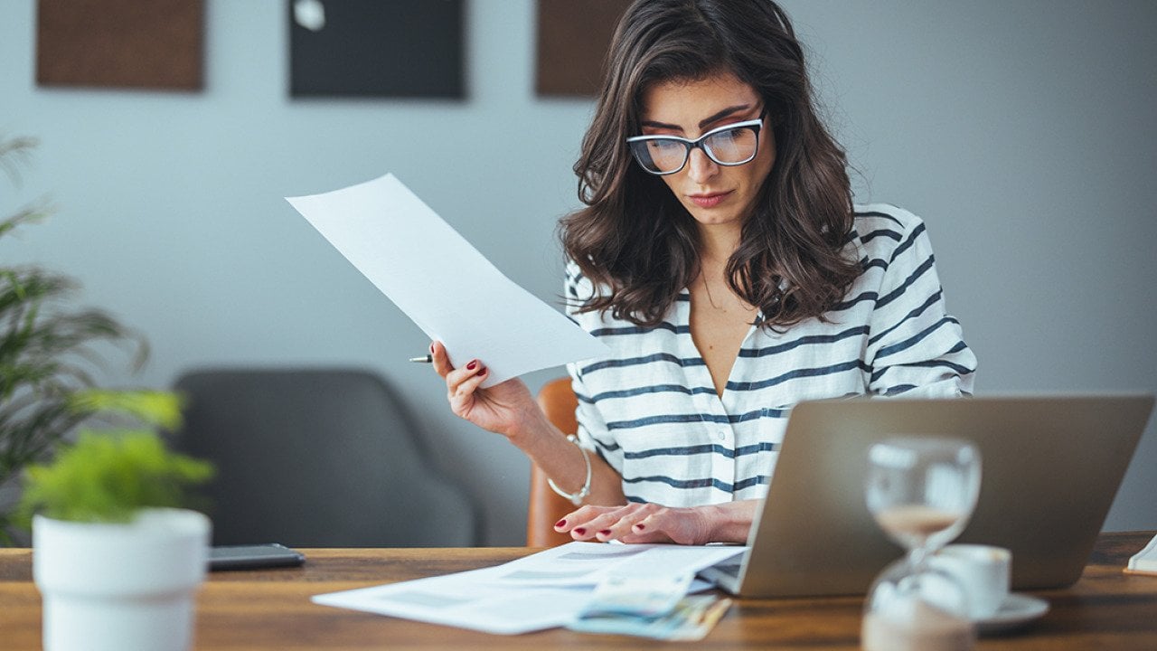 A businesswoman reading finance documents in an office.
