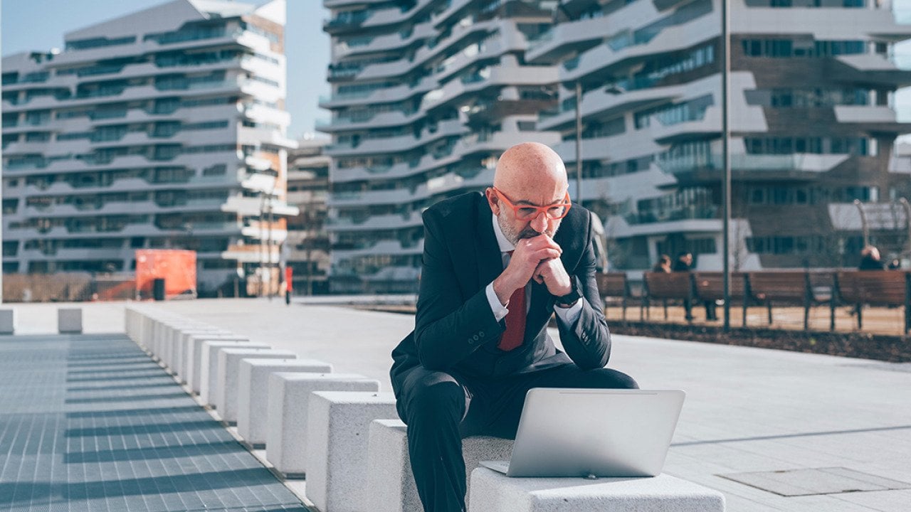 Businessman sitting outdoors and concentrates on his laptop.