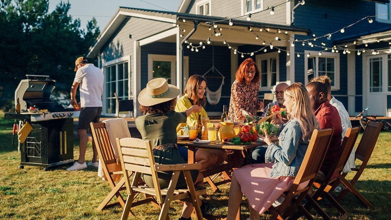 Family and friends dining outside a home during a barbecue dinner party.