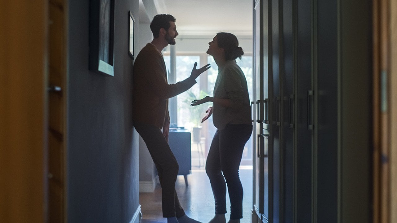 A couple fighting in a hallway of their apartment.