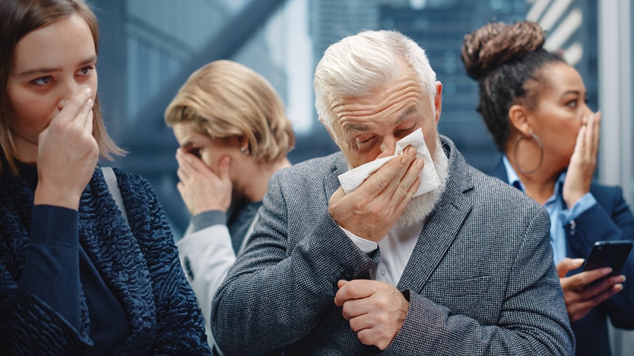 A middle-aged man sneezes in a crowded elevator.