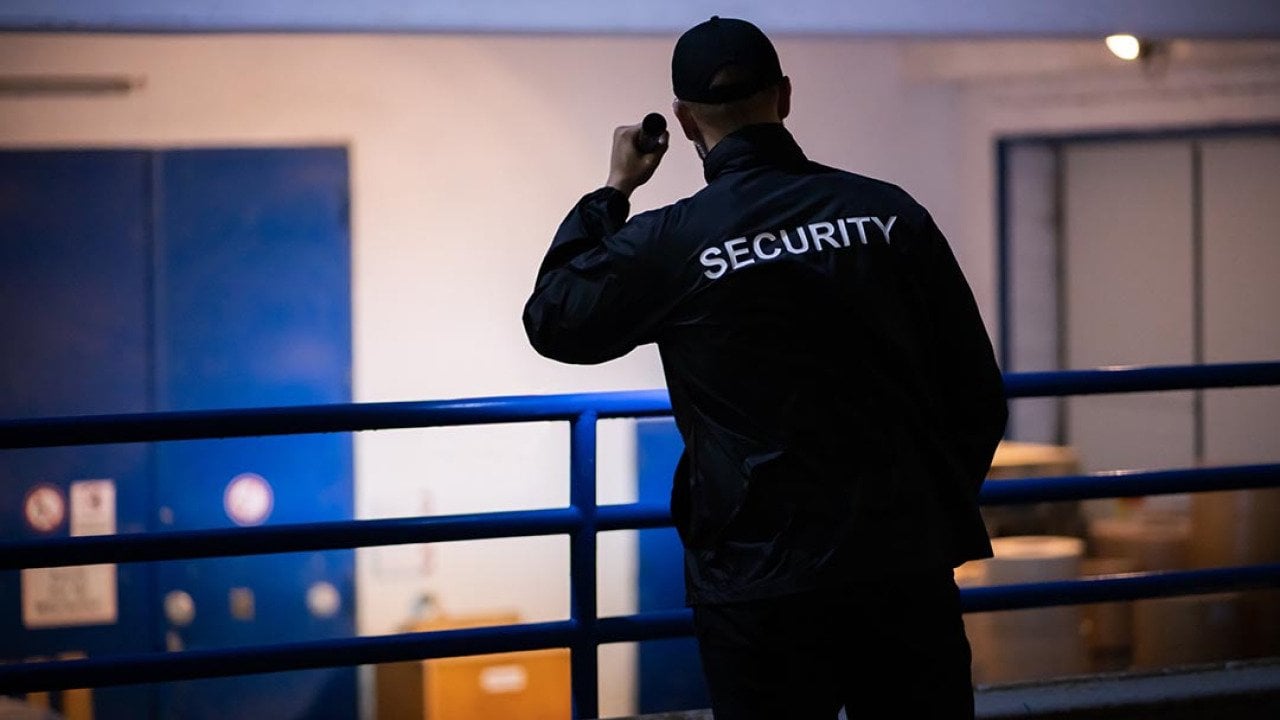 A person standing on a loading ramp outdoors at night wearing dark clothes with the word 