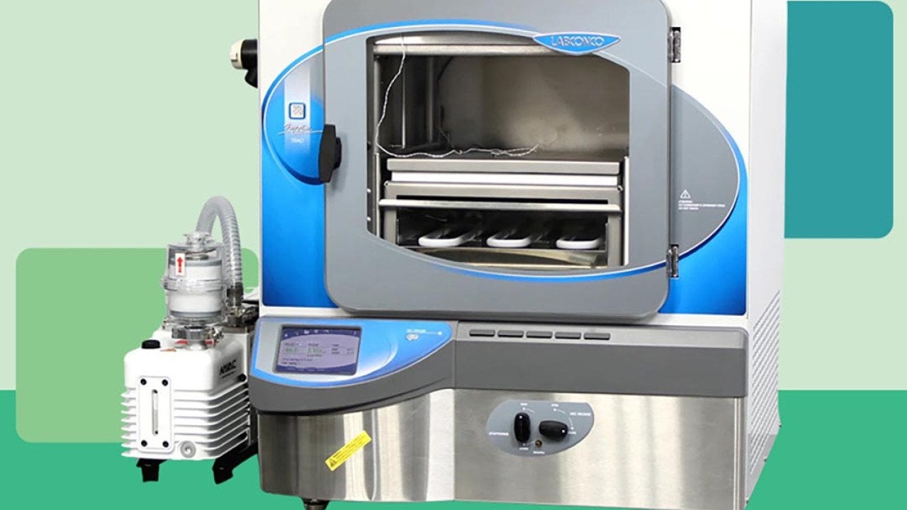 Photo of modern lab freeze dryer cut out against a stylized background of different shades of green blocks. 