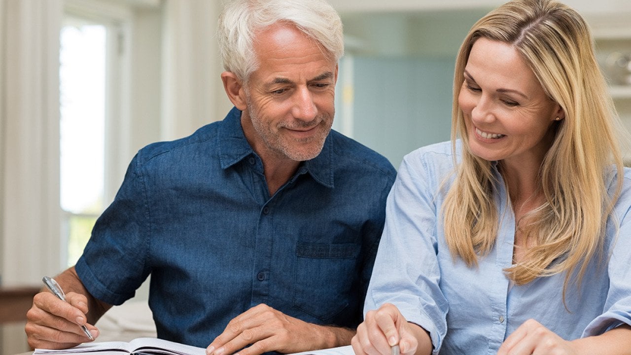 A middle-aged couple reviewing documents at home.