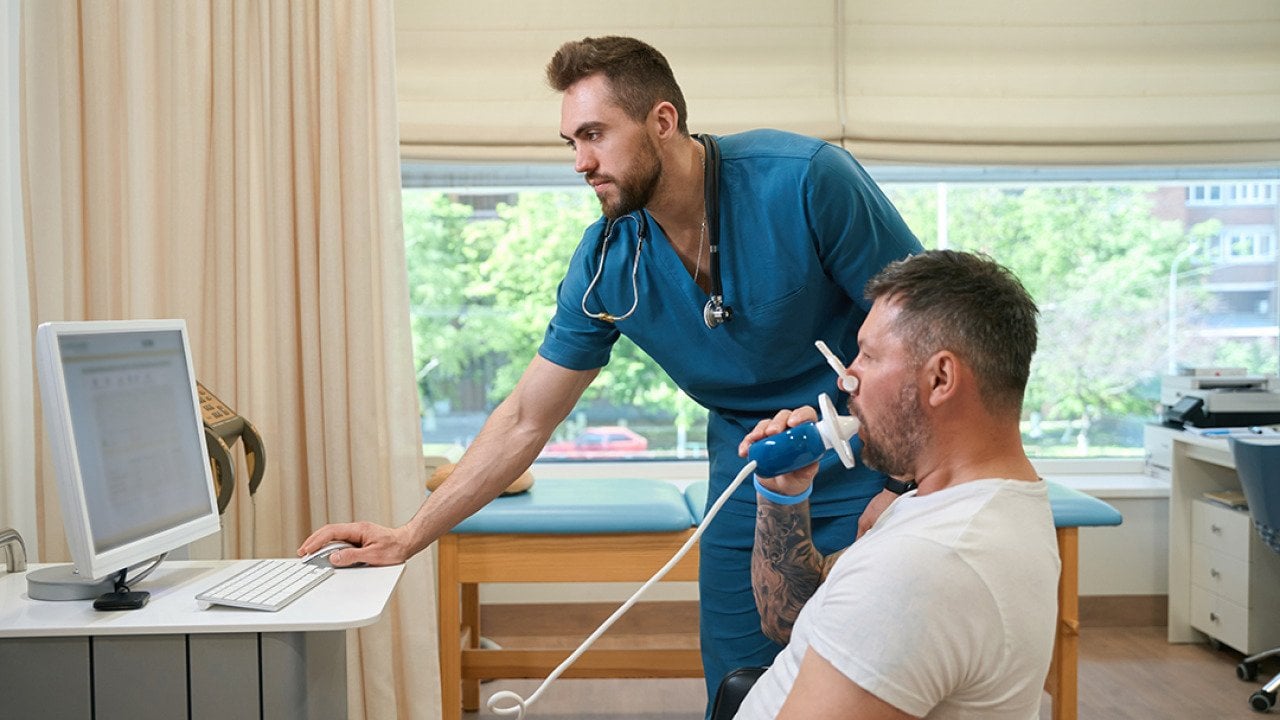 A pulmonologist checking a patient's lung functions during a spirometry test.