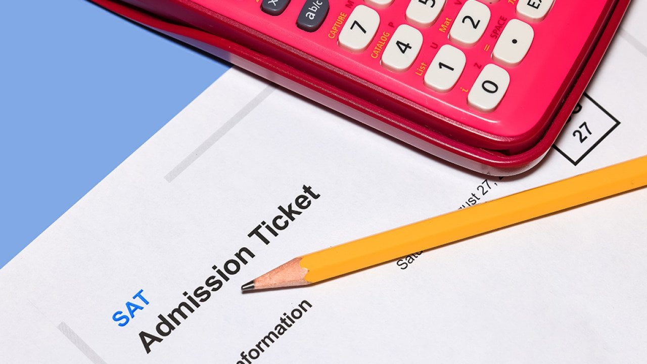 An SAT admission ticket under a pencil and calculator.