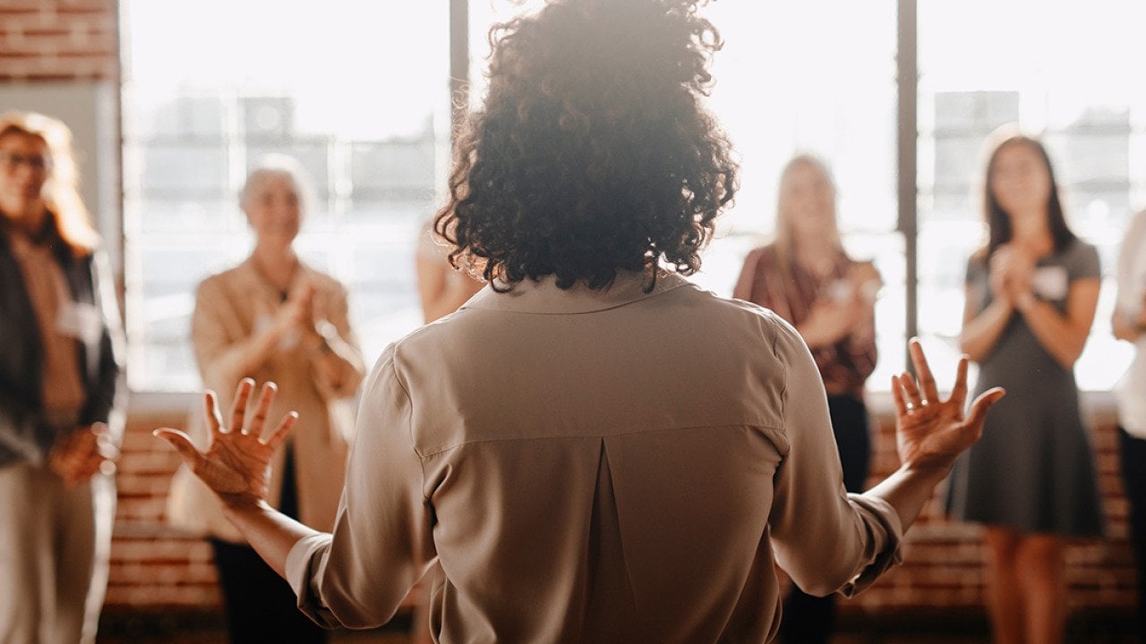 A woman in front of her colleagues leading a talk in the workplace.