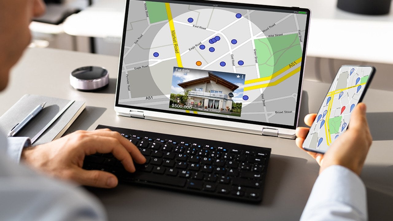 Person looking up a map view of a property's location using a laptop and a phone.