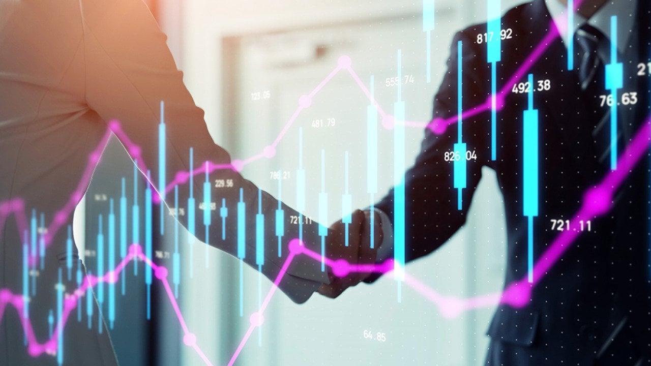 Stock chart graphics over business people shaking hands.