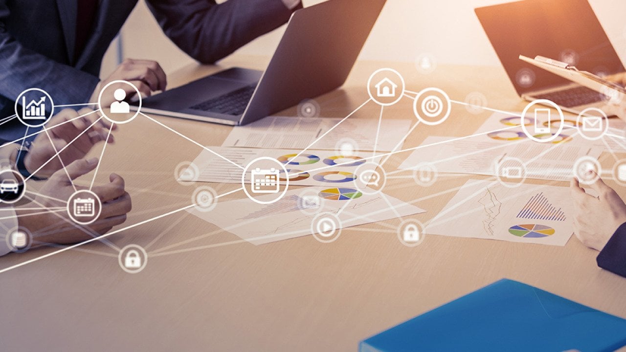 Business people in a meeting with an overlay of networking and communication icons.