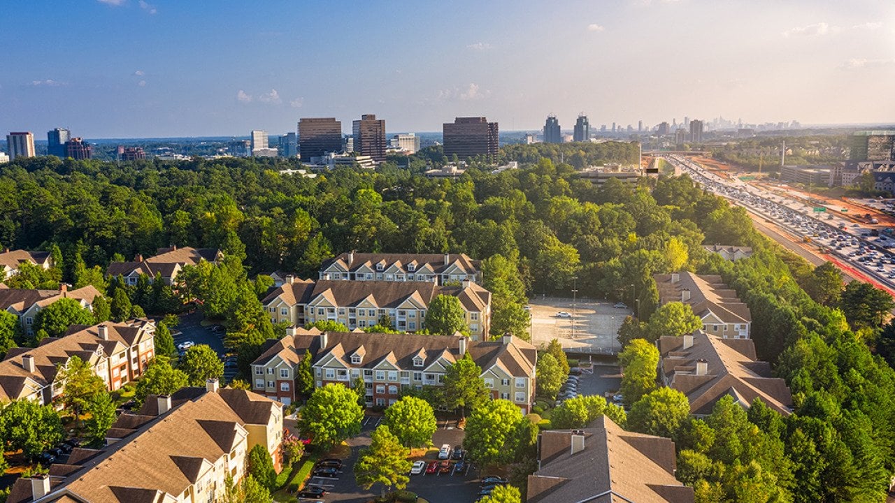 Condos in Atlanta suburbs just next to Highway GA 400 with blue sky and downtown in background.