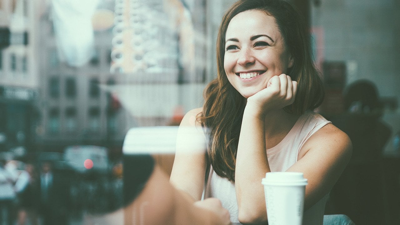Couple sitting by the window glass side of a cafe, reflecting a great view of the city outdoors.
