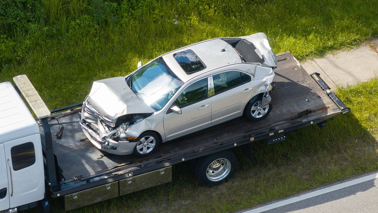 A damaged car loaded on a tow truck from the accident site.