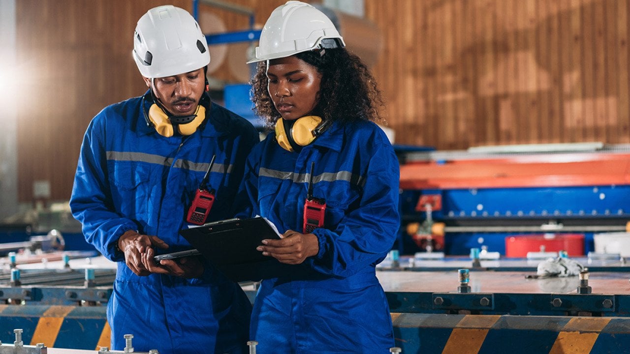 A pair of industrial workers inspect their factory's machines.