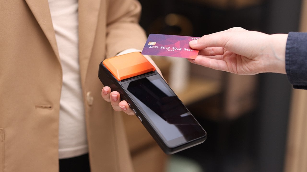 Person taps a business credit card on a payment terminal.