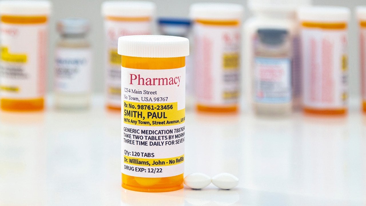 A generic prescription medicine pill bottle in front of a row of other pill bottles.